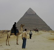 A guard patrolling on camel.  Behind, a tourist and driver on another camel.