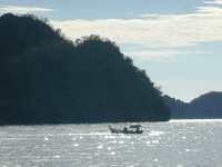 As the ocean twinkles in the late sun, a fishing boat passes (1600x1200, 350.1 kilobytes)