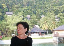 Gloria waits for our departure boat.  Behind her is the main office; above and behind that are the hill villas, where we stayed on our first two visits. (685x500, 87.3 kilobytes)