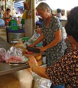 While this woman chops with a cleaver as her customer watches.