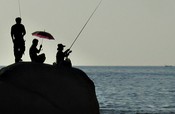 Line fishing on the rocks at the end of the beach