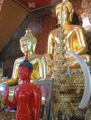 Buddhas, including unusual red, an elephant tusk, a <em>hti</em> which should be at the top of a chedi, and a photo of the king.