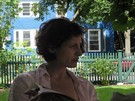 Sarah relaxes with the Sunday paper, in front of the very blue house across the street.